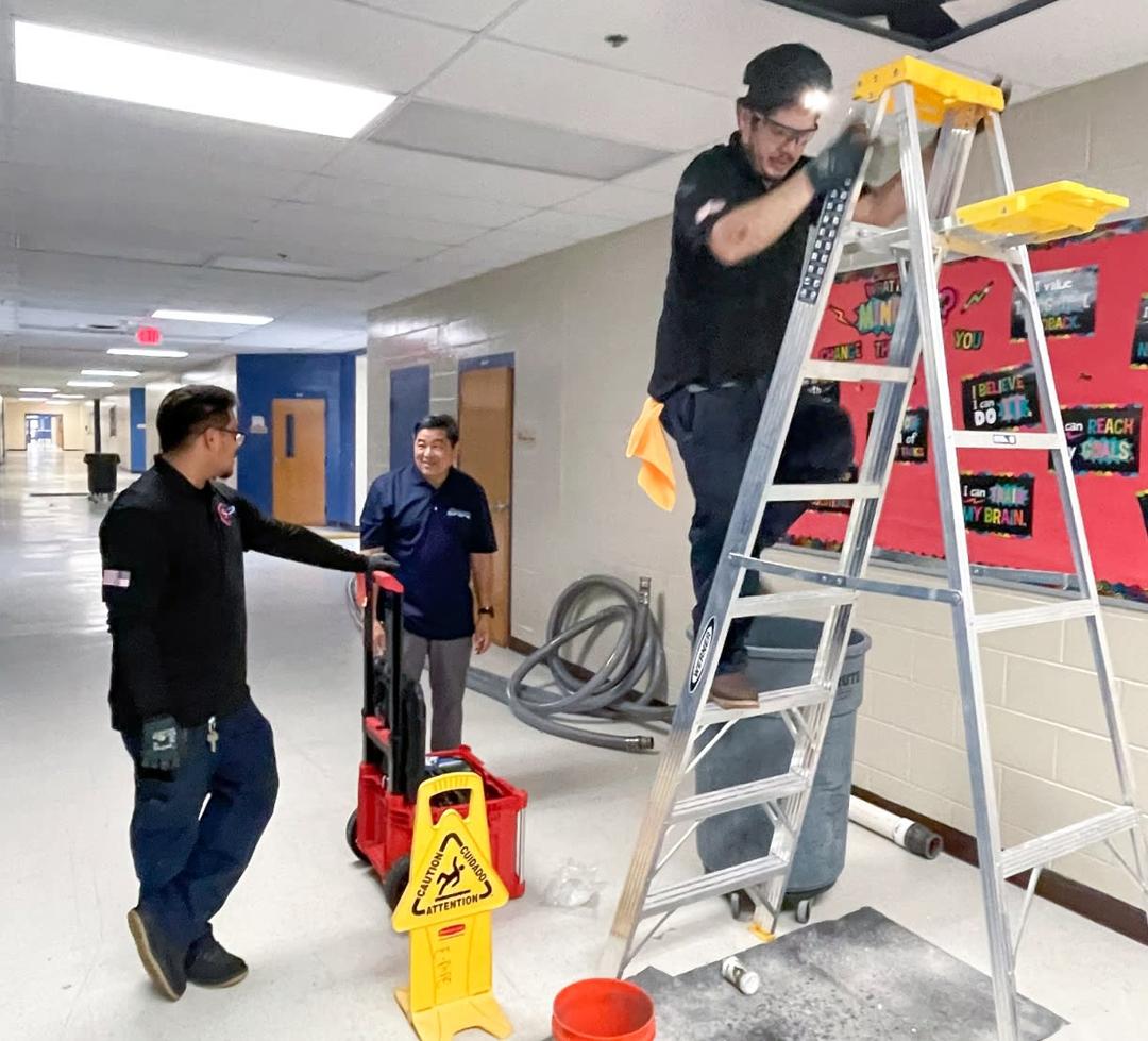 Workers climbing a ladder inside a school