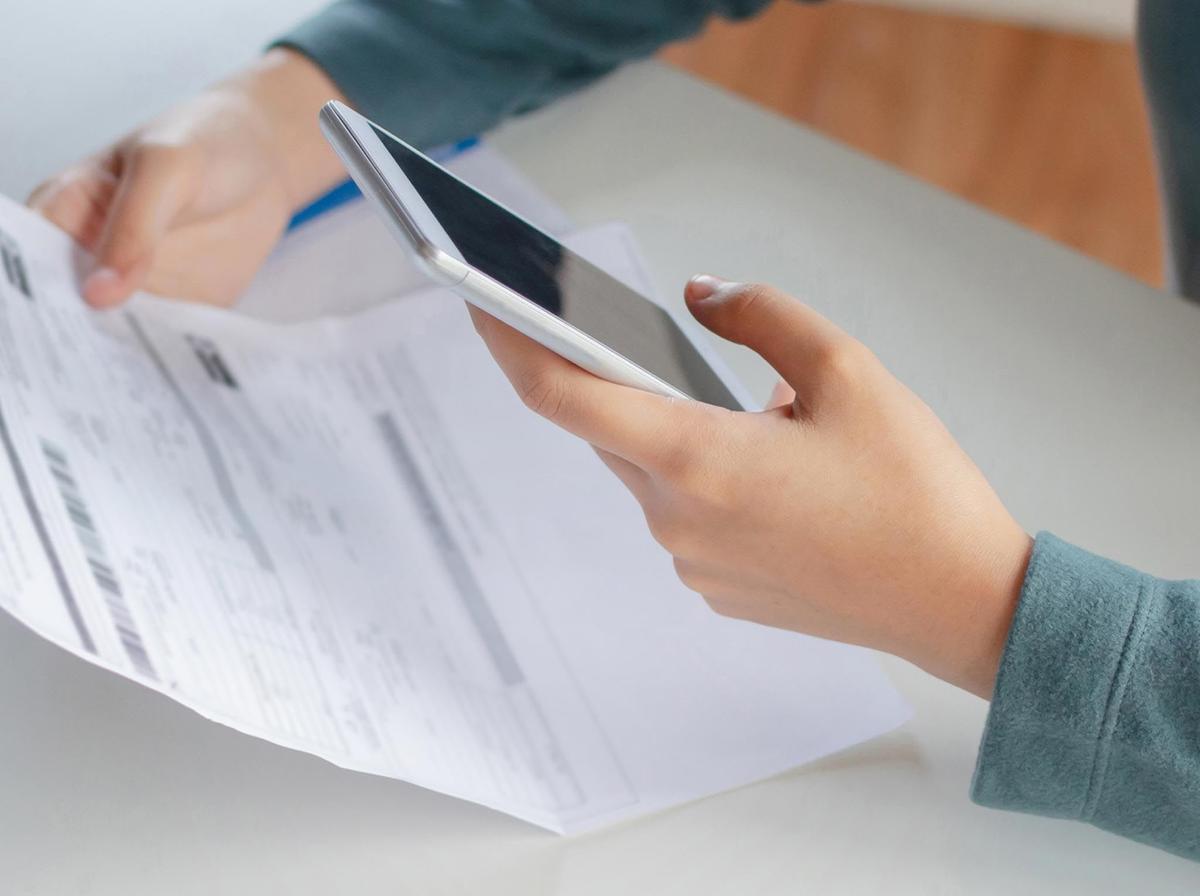 Someone looking over a bill while on their phone