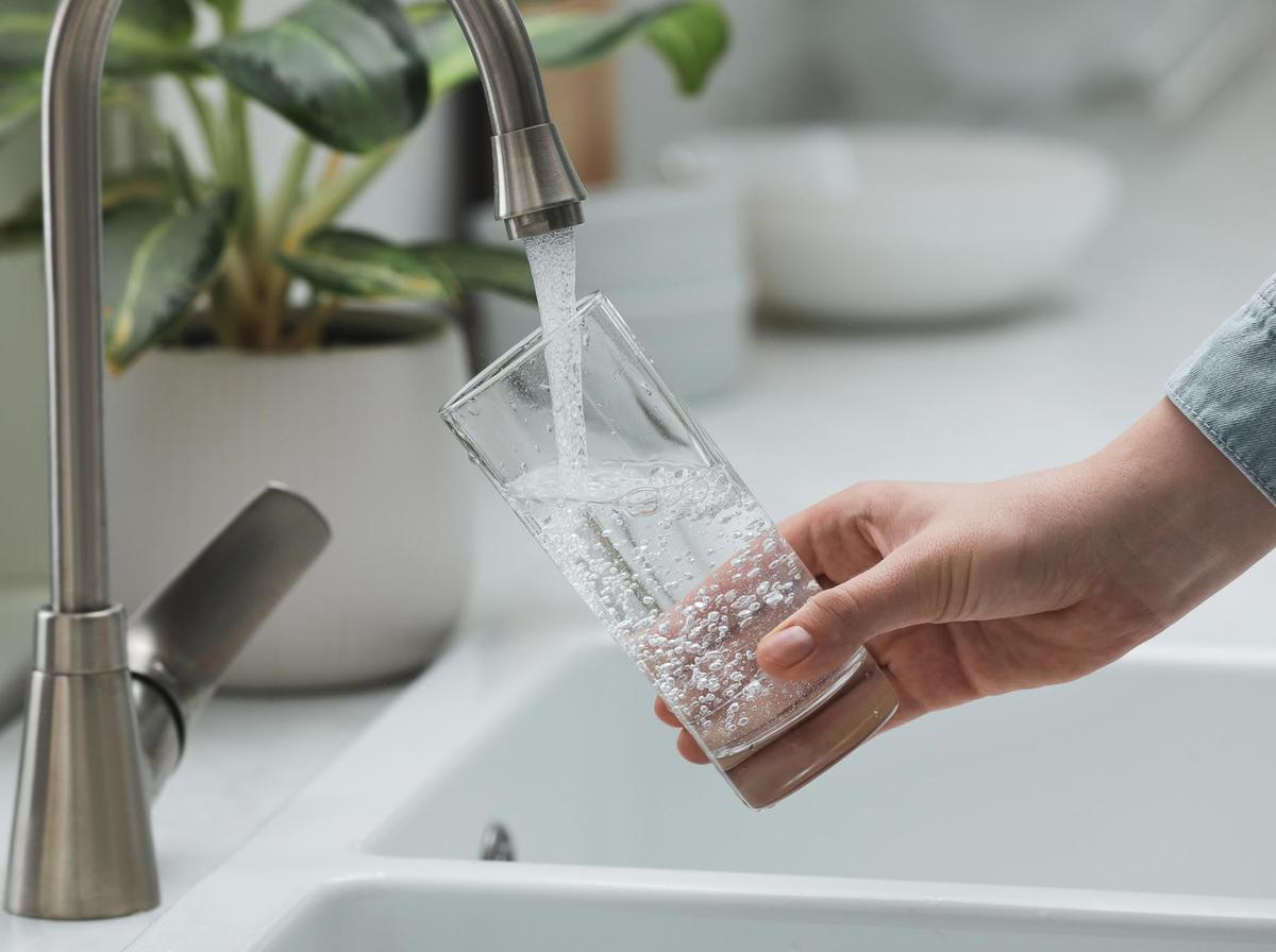 Someone filling a glass with water from a faucet