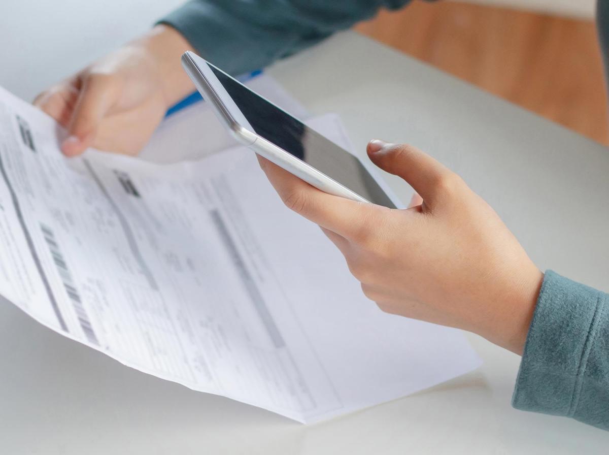 Someone looking over a bill while on their phone