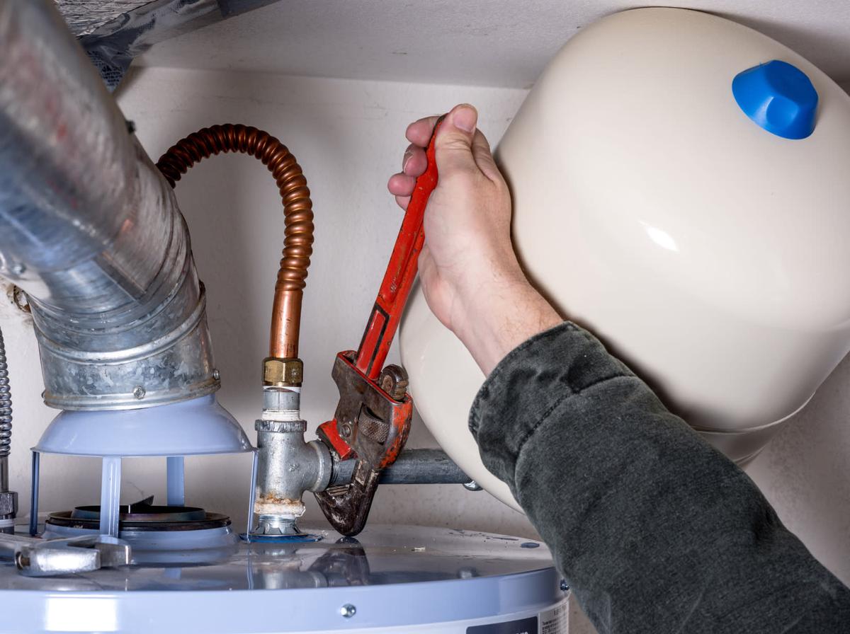 Someone using a wrench on a water heater