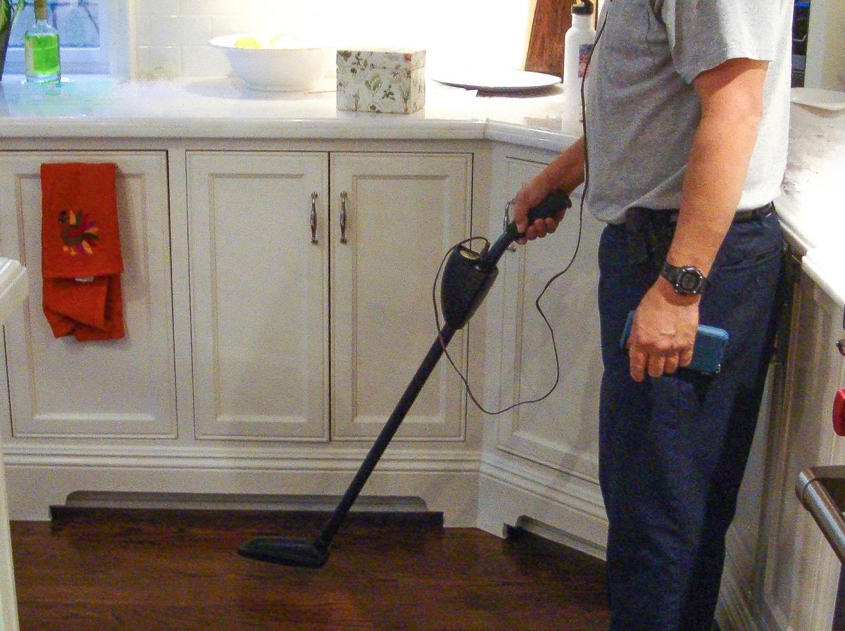 A technician looking for leaks in a kitchen